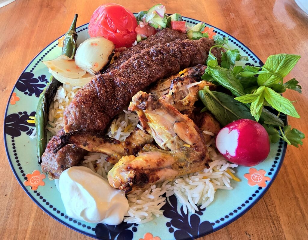 Serving the Persian-Style Chicken Wings (Joojeh Kabob) with traditional accompaniments: saffron rice, grilled tomato, grilled onion, grilled chilli, Shirazi salad, sabzi khordan, radishes, yogurt, and Persian Lamb Kebabs (Kabob Koobideh)